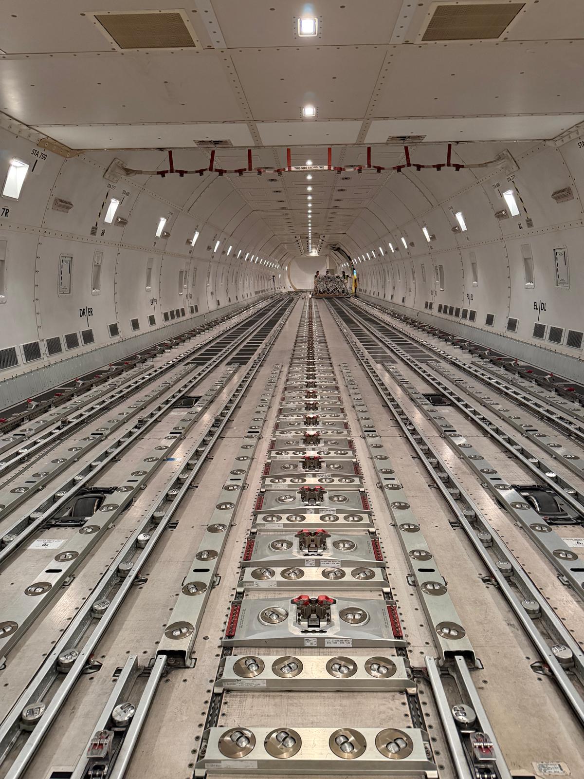 Empty widebody freighter main deck showing roller floor, cargo rails and pallet locks