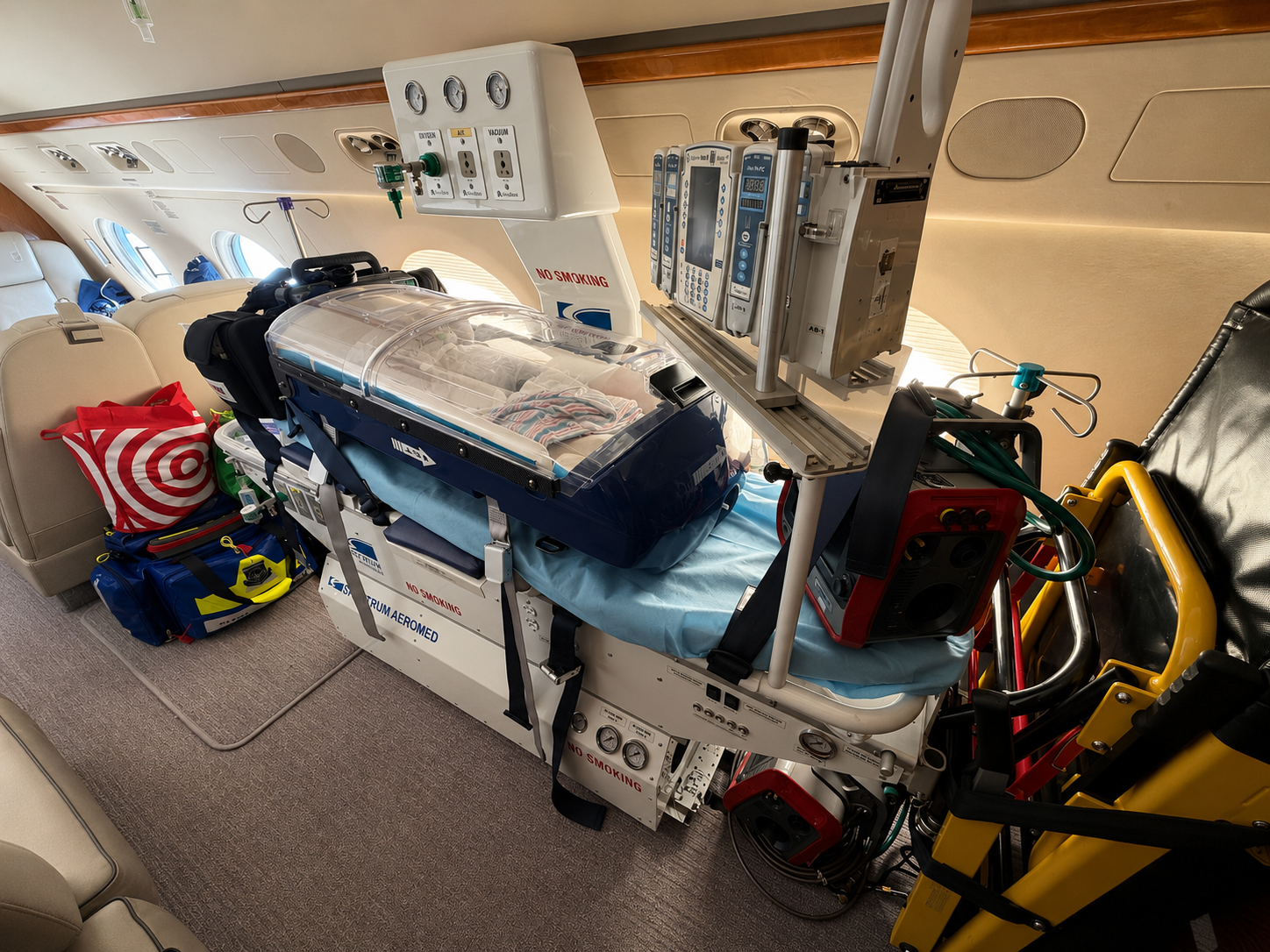Neonatal transport incubator secured to a stretcher base inside an aeromedical cabin