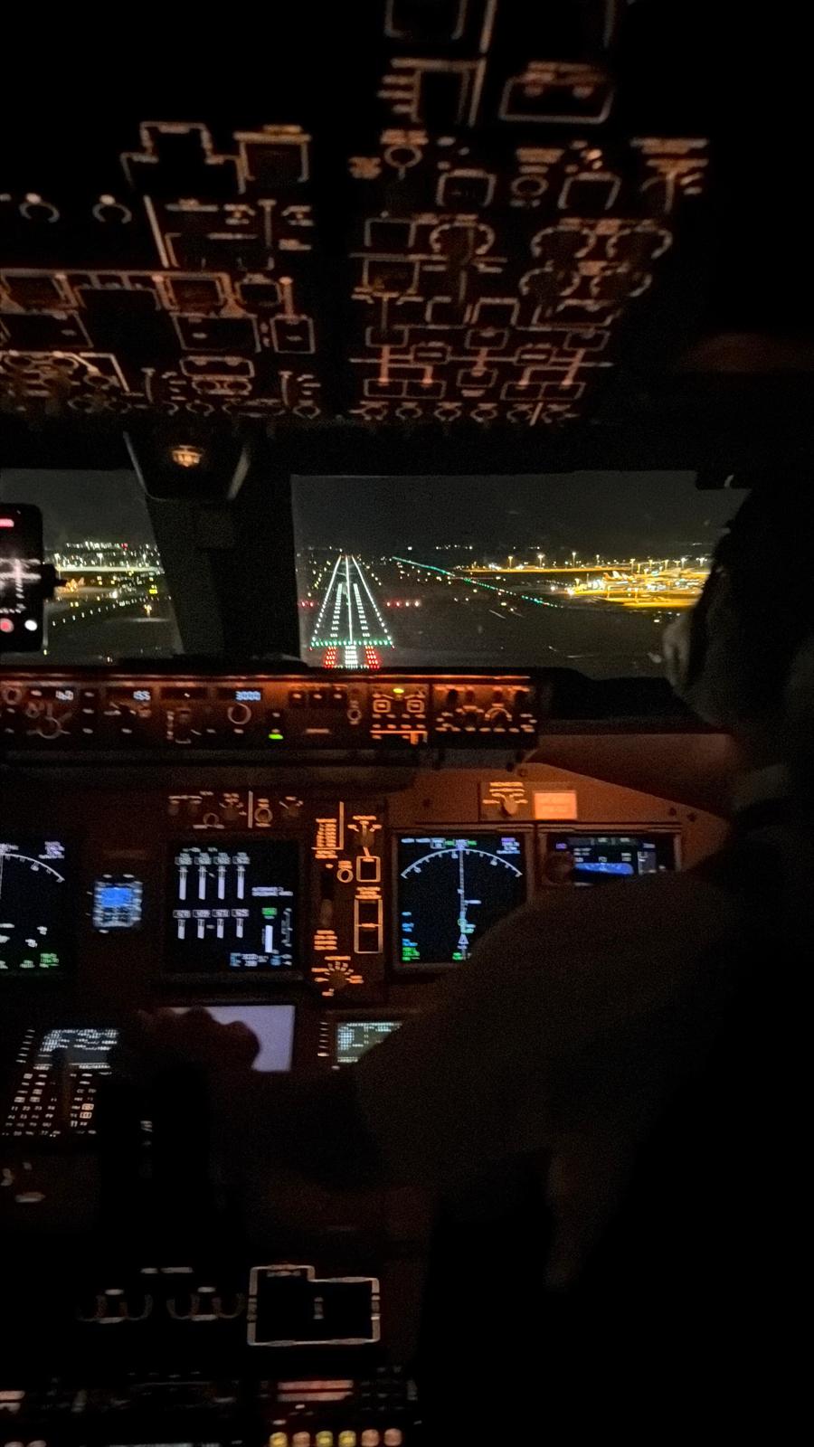 Flight deck view of a lit runway on short final at night